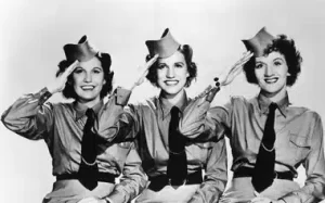 Vintage image of The Andrews Sisters in military uniform, rendering a salute in a classic patriotic pose.